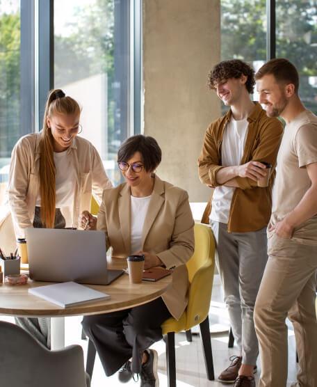 People in an office surrounding a computer