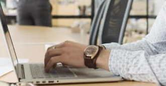 Closeup of an individuals hands typing on a laptop.